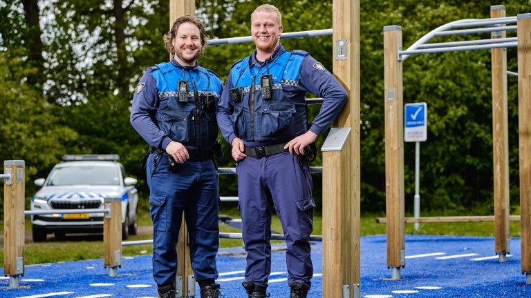 Jeugdboa's Luuk en Daniël die buiten voor een sporttoestel staan in uniform. Op de achtergrond een bosrijke omgeving en de dienstauto.